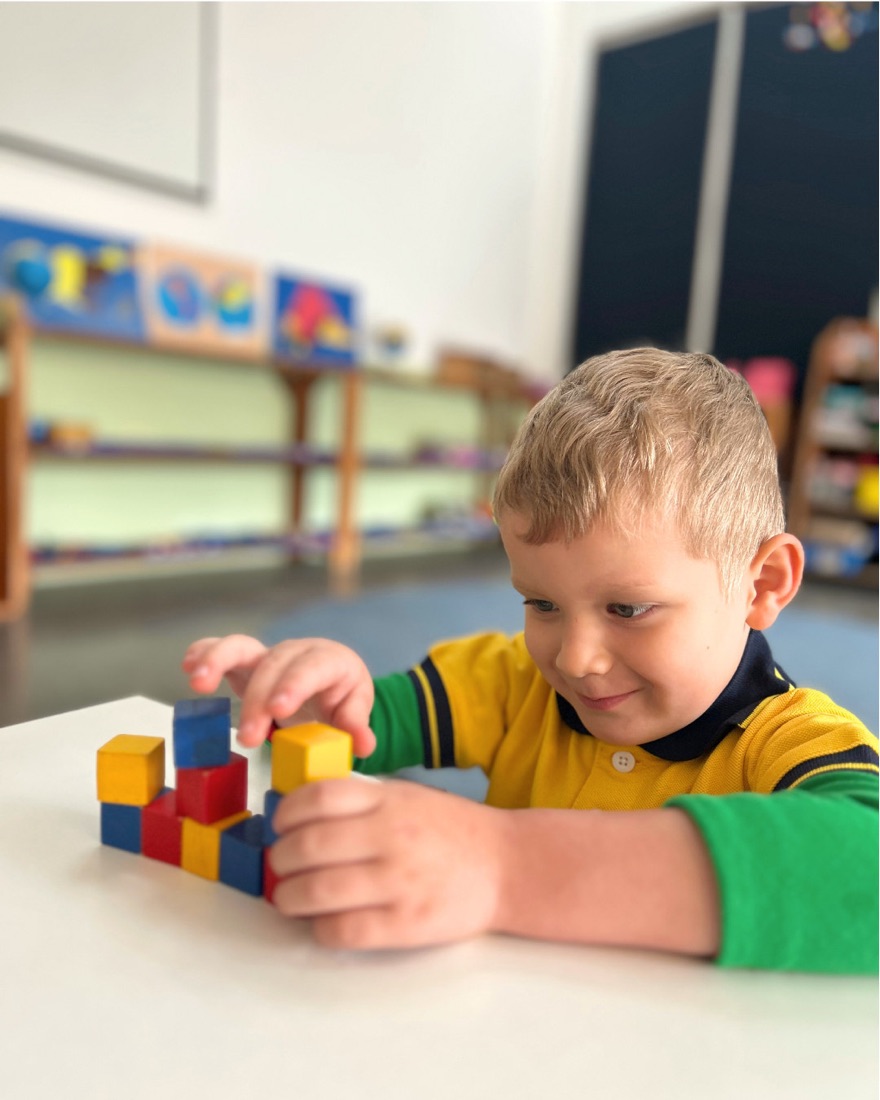 Niño de preprimaria construyendo con bloques de colores